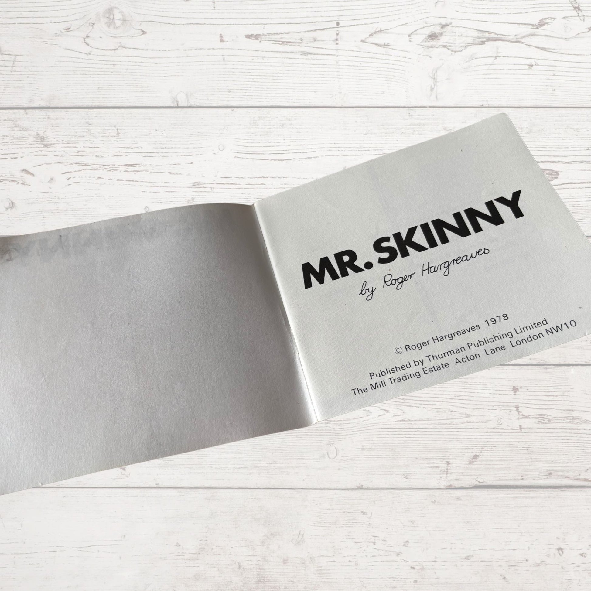 Open book with 'MR. SKINNY' title on a light wooden surface