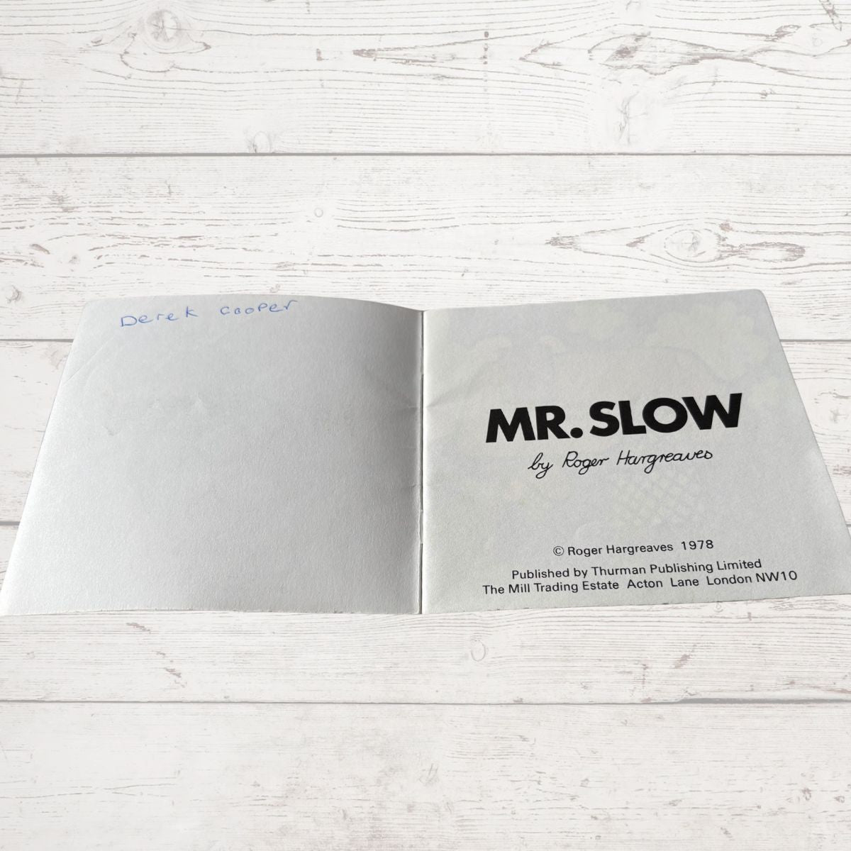Open book with 'MR. SLOW' title on a wooden surface