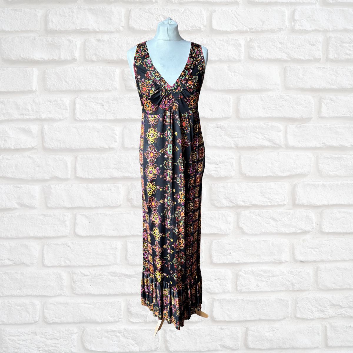 Psychedelic patterned dress on a mannequin against a white brick wall background