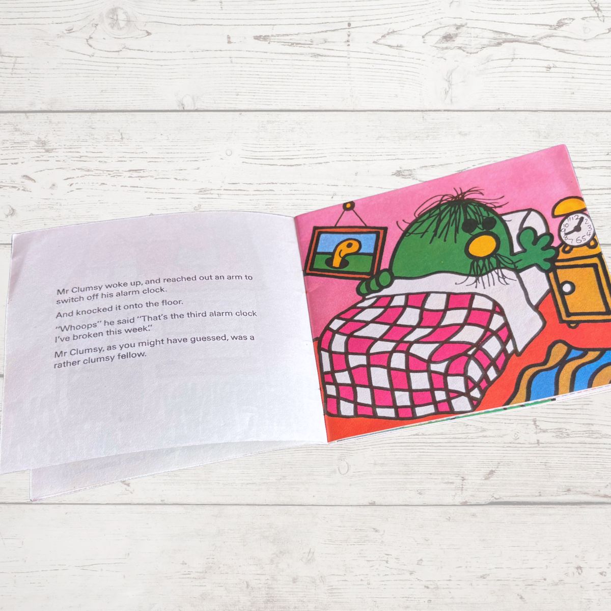 Open book with a colorful illustration of a green character and text on a wooden surface