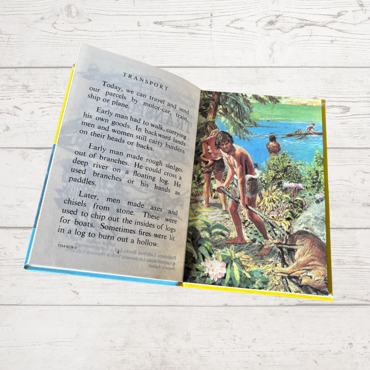 Open book with a historical illustration and text on a wooden surface