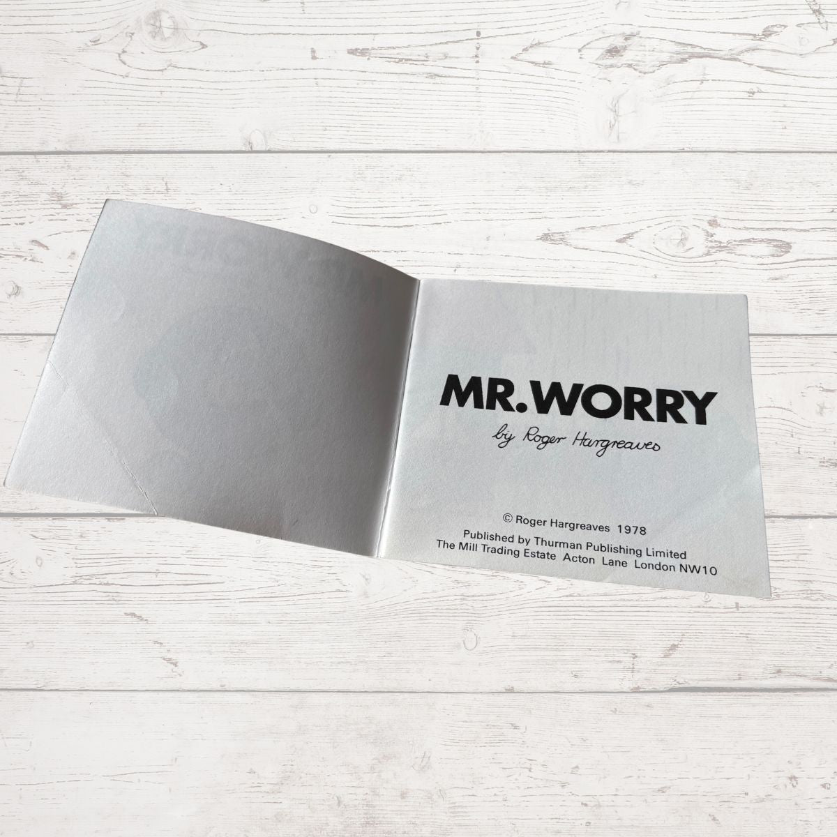 Open book titled 'MR. WORRY' by Roger Hargreaves on a light wooden surface.
