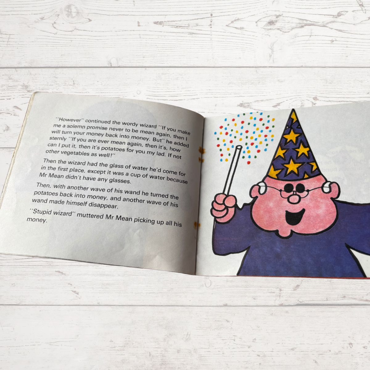 Open book with a cartoon character on a wooden surface