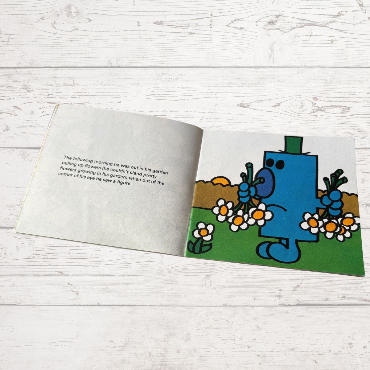 Open book with a cartoon character on a wooden surface