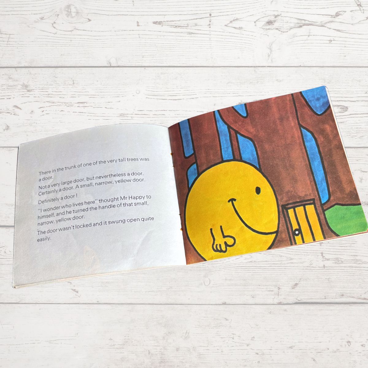 Open book with a cartoon illustration of a smiling yellow face and a door on a wooden surface