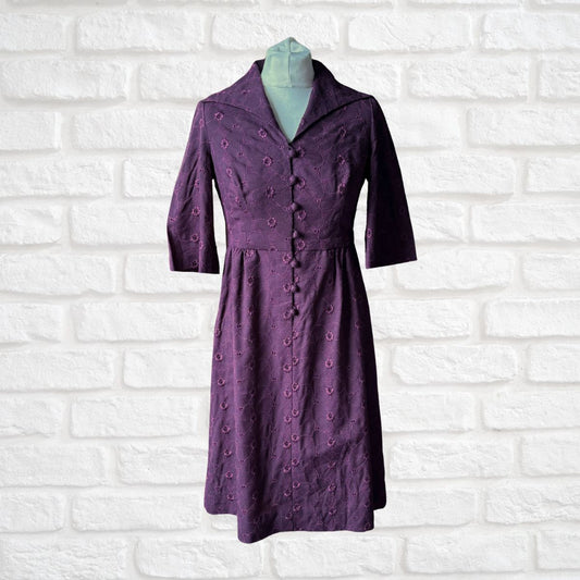 Purple dress on a mannequin against a white brick wall background