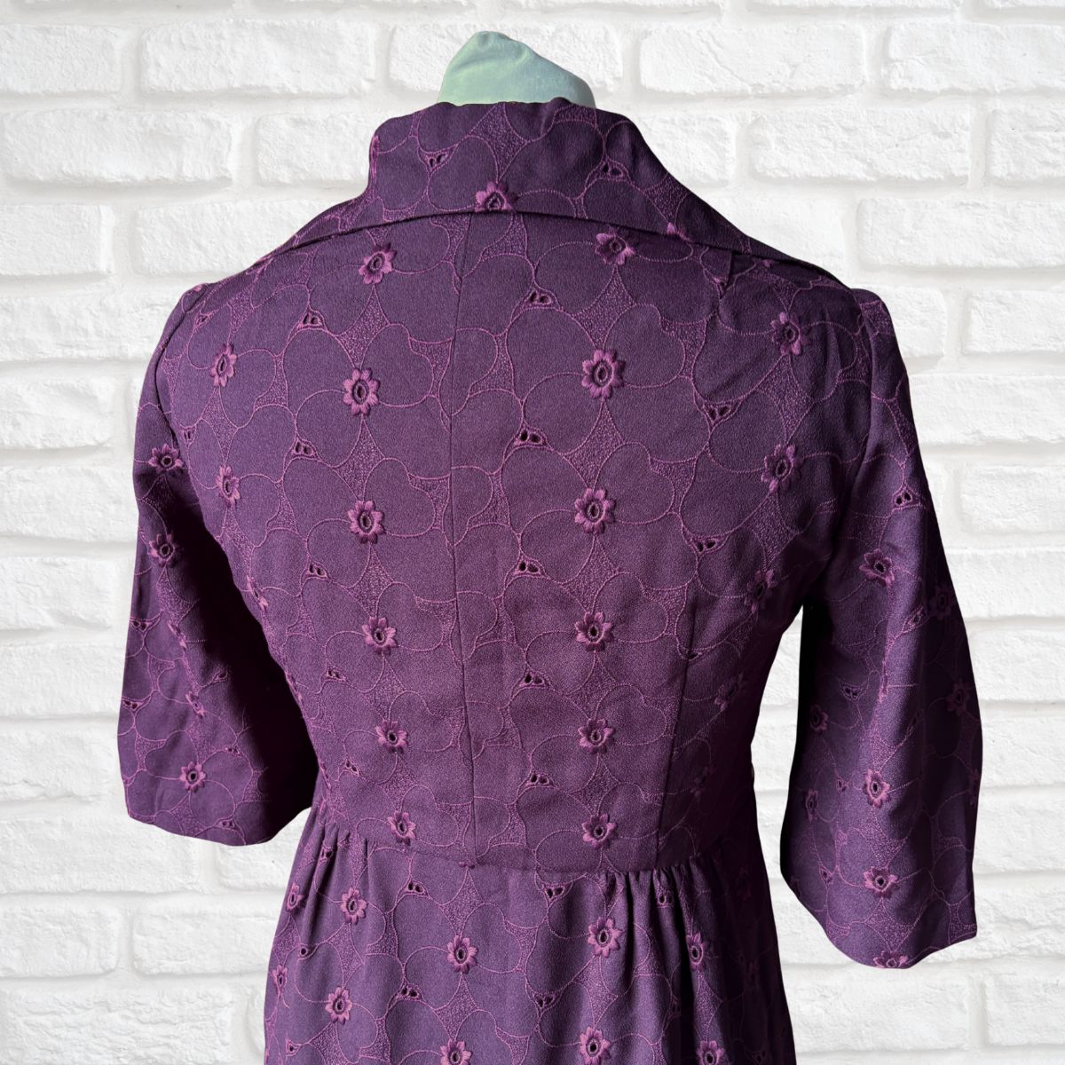 Purple dress with floral pattern on a white brick wall background