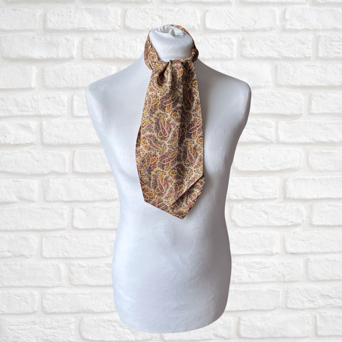 Patterned cravat on a mannequin against a white brick wall background