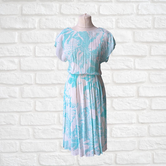 A vintage Betty Barclay midi dress featuring a white and turquoise floral print, displayed on a mannequin against a white brick wall background.