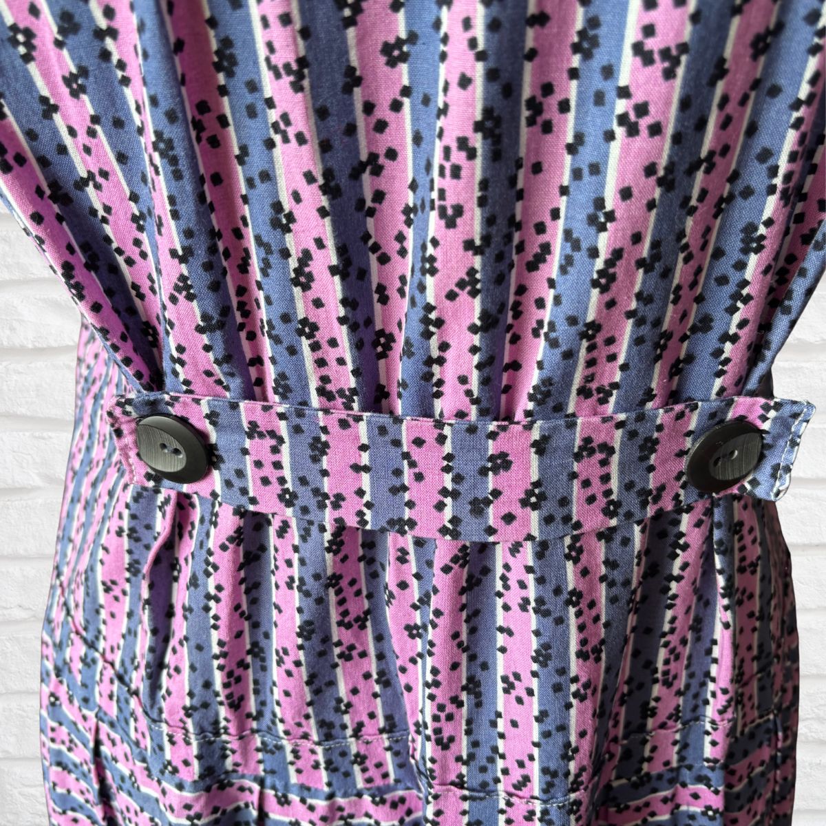 Close-up of a patterned dress with pink and blue stripes and black speckles