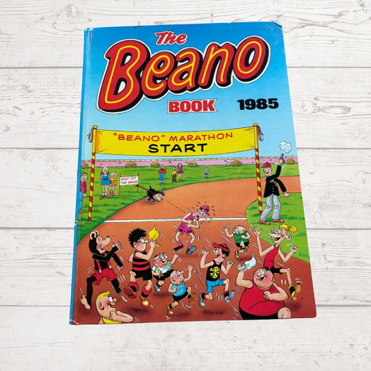 1985 'The Beano' book cover with cartoon characters on a wooden surface