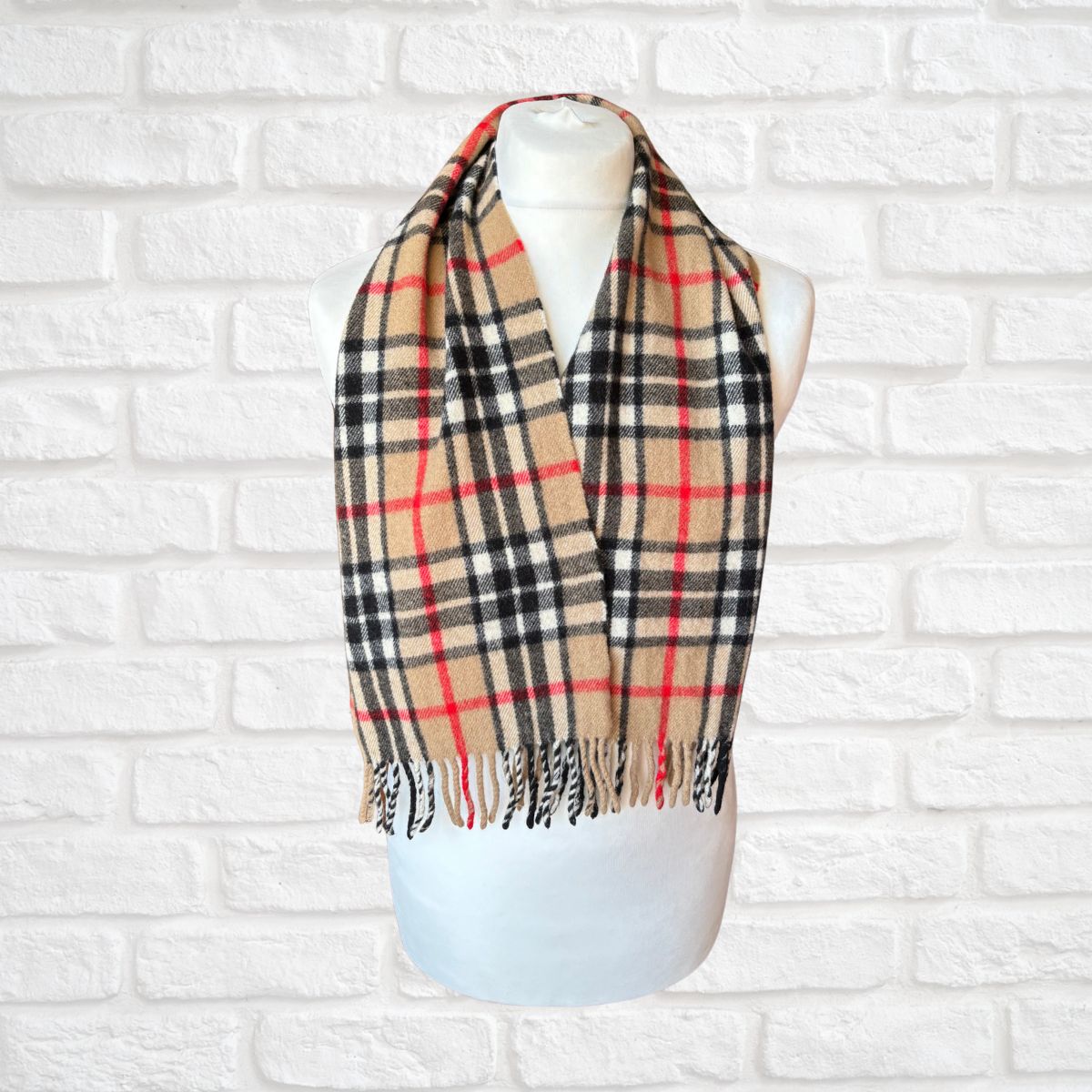 Plaid scarf on a mannequin against a white brick wall background