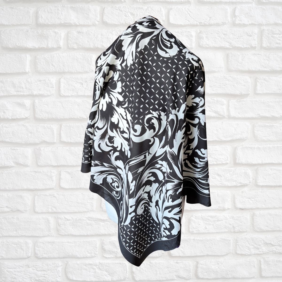 Black and white patterned scarf draped over a white brick wall