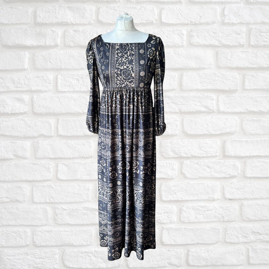 Black patterned dress on a mannequin against a white brick wall.