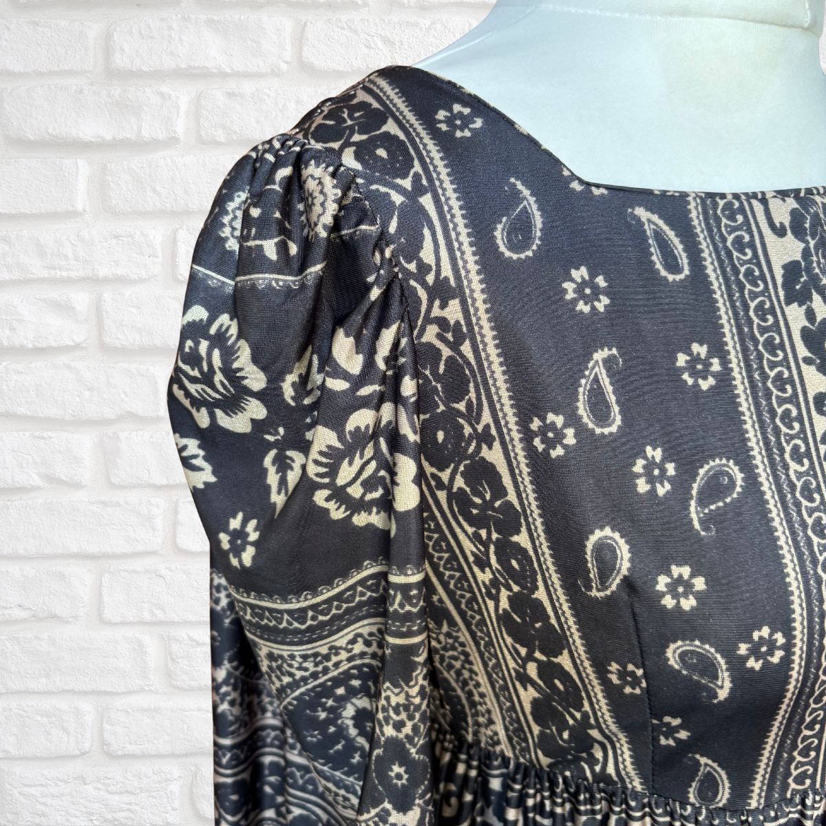 Black and white patterned fabric draped over a mannequin against a white brick wall.