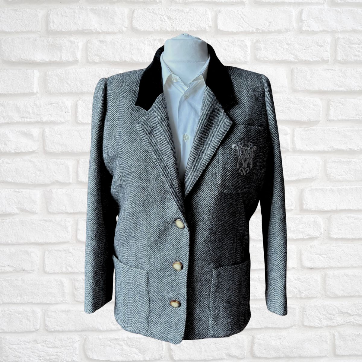 Gray blazer with black collar on a mannequin against a white brick wall background