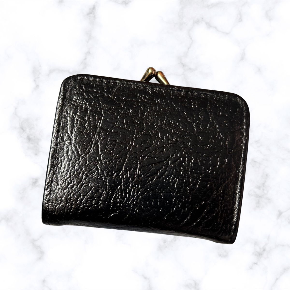 Black leather wallet on a white marble background