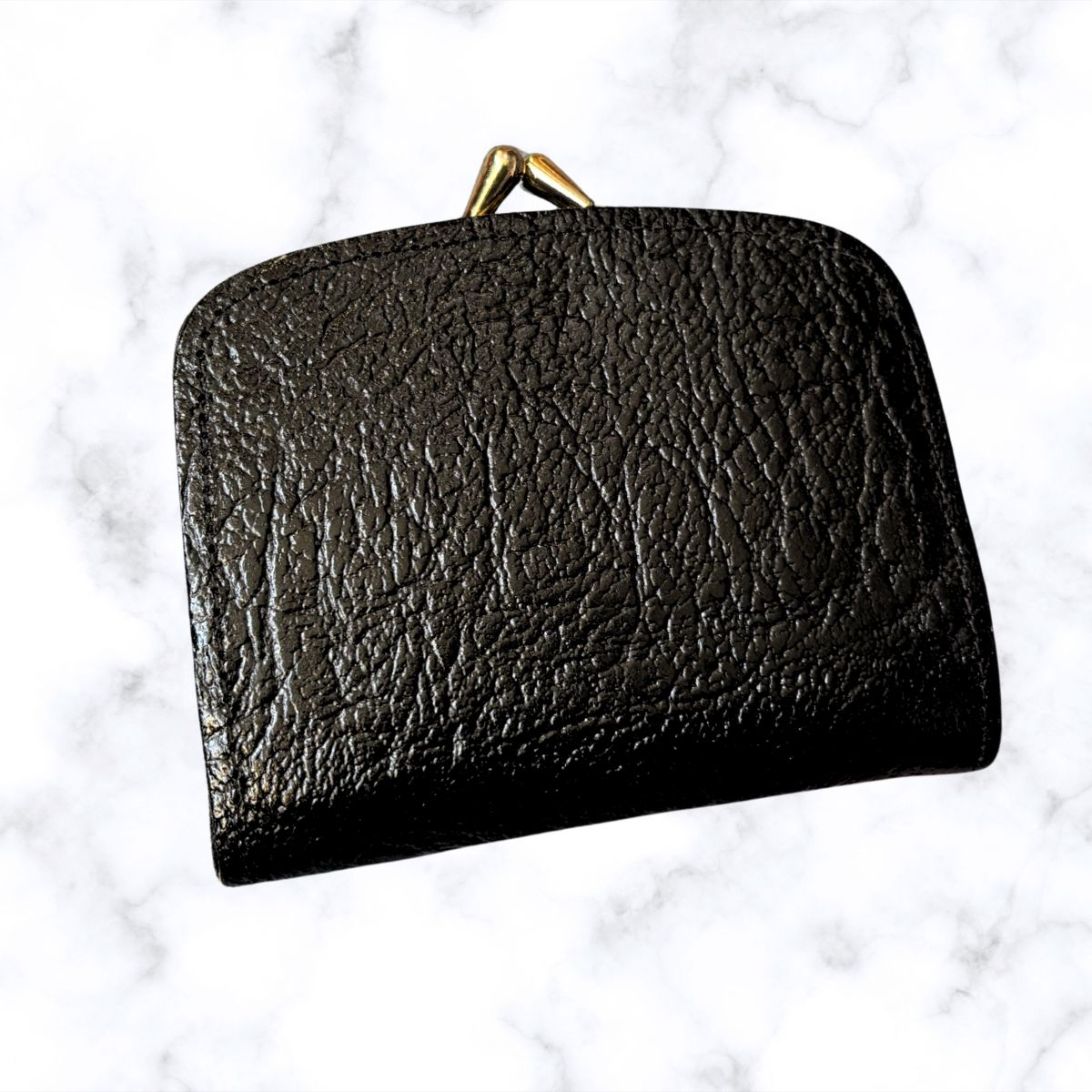 Black leather clutch with gold clasp on a light gray background