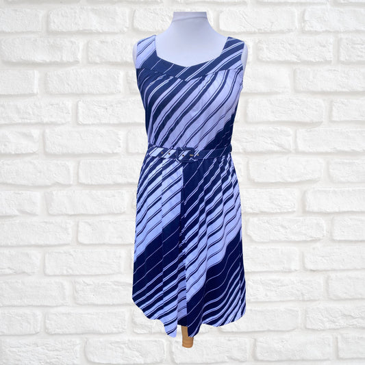 A navy blue and white striped vintage sundress with wide straps, a v-neck, and a matching belt, displayed on a mannequin against a white brick wall.