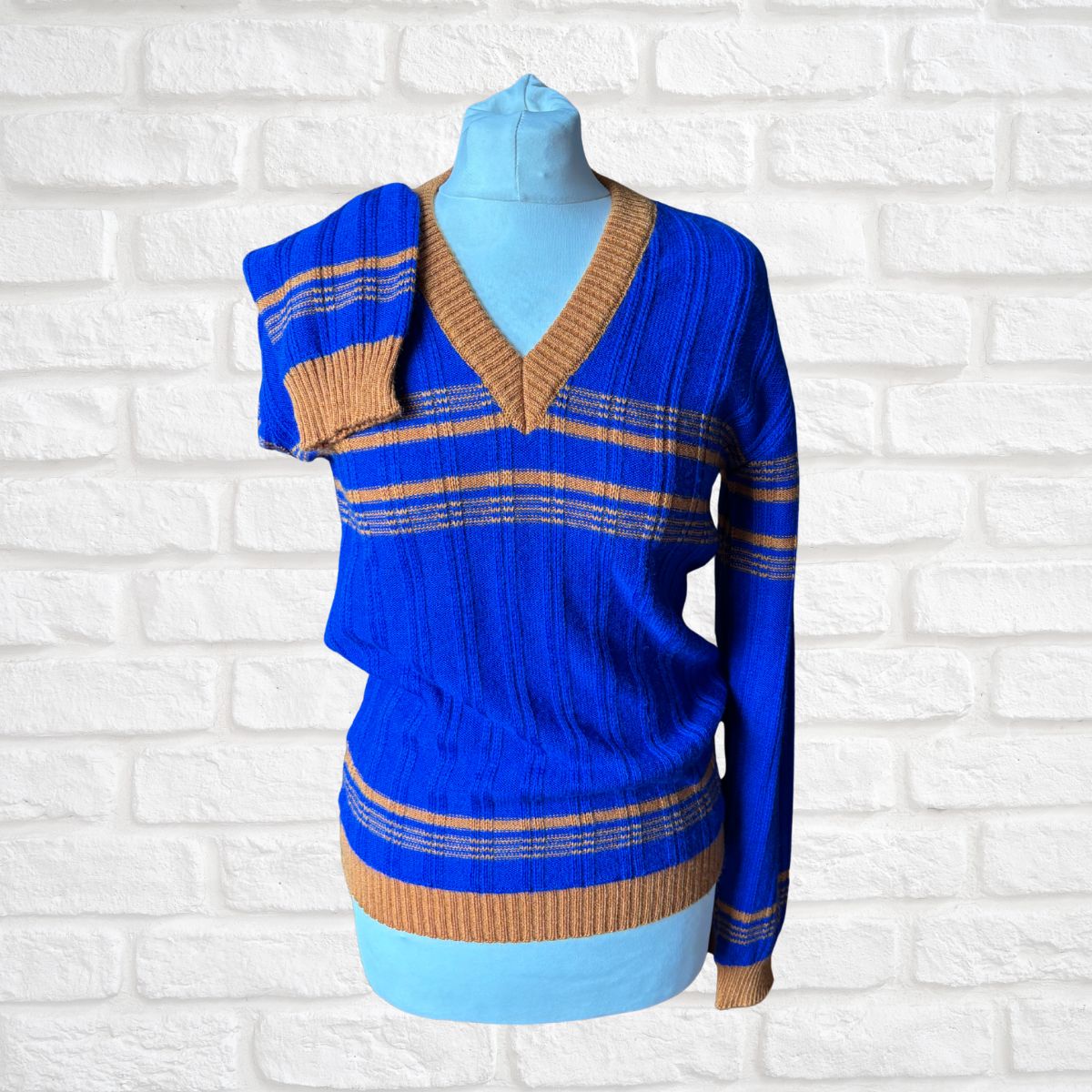 Blue and brown striped dress on a mannequin against a white brick wall background