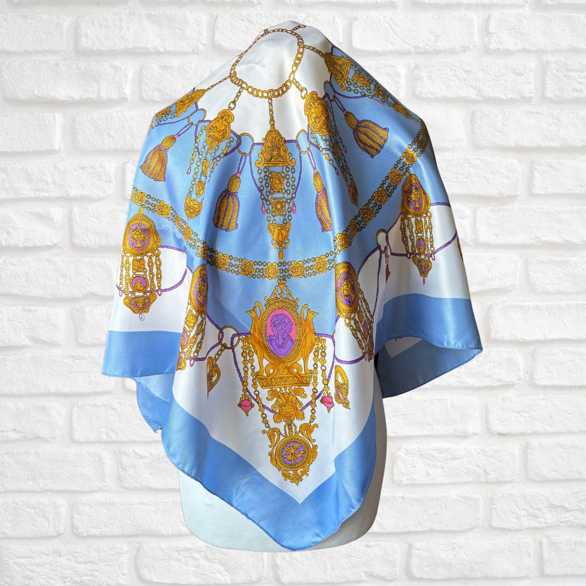 Decorative scarf with jewelry design on a white brick wall background