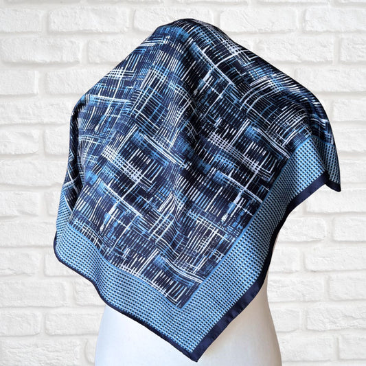 Blue patterned scarf on a mannequin against a white brick wall background