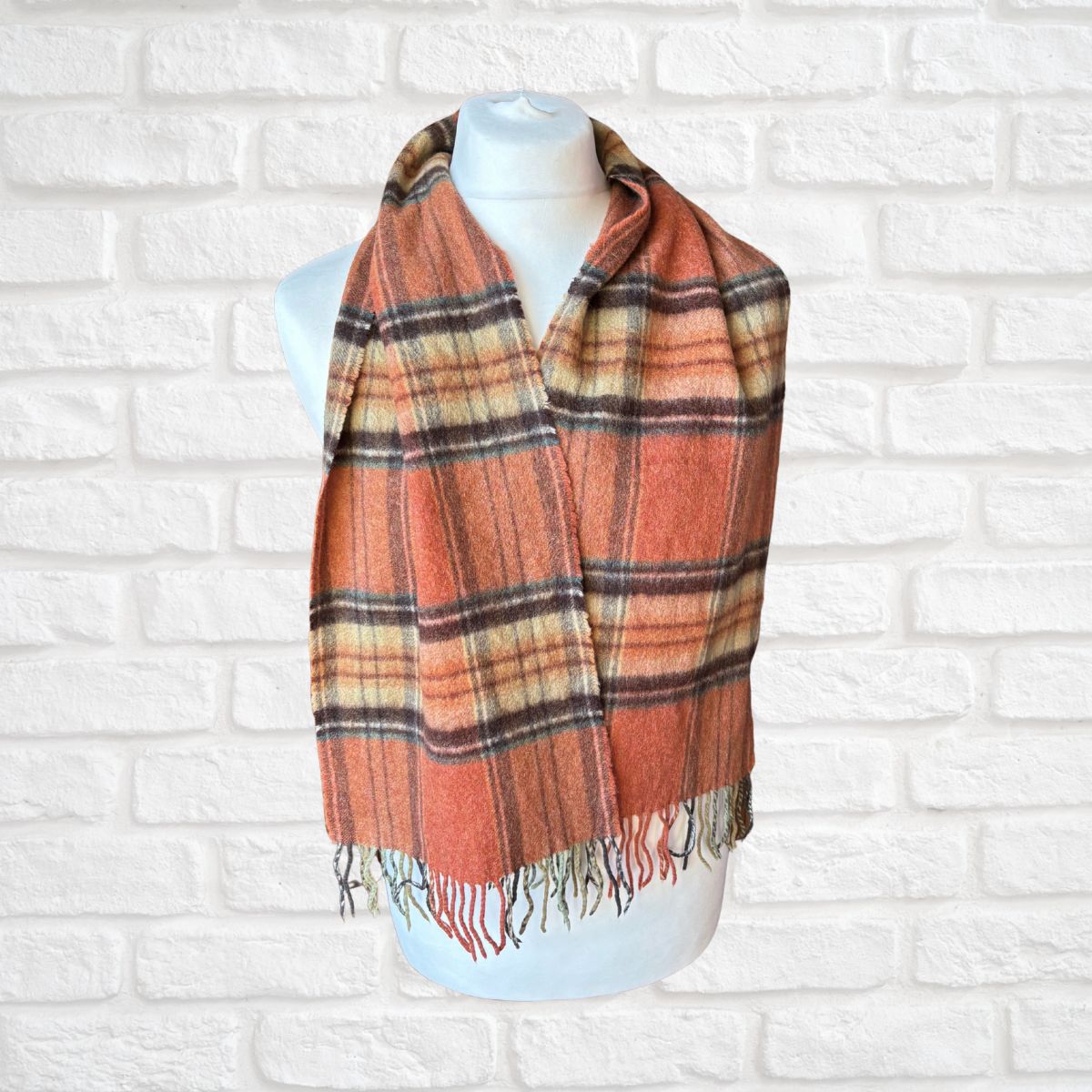 Plaid scarf on a mannequin against a white brick wall
