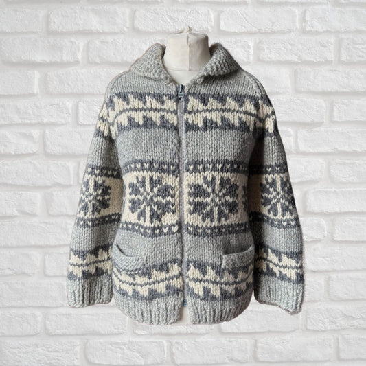 Knitted sweater with a snowflake pattern on a mannequin against a white brick wall.