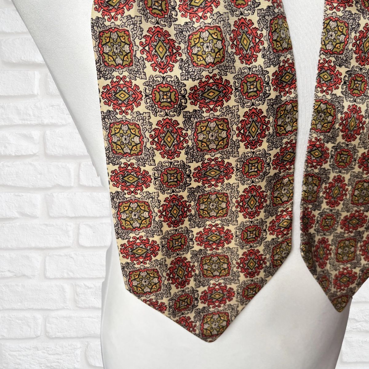 Patterned tie on a mannequin against a white brick wall background