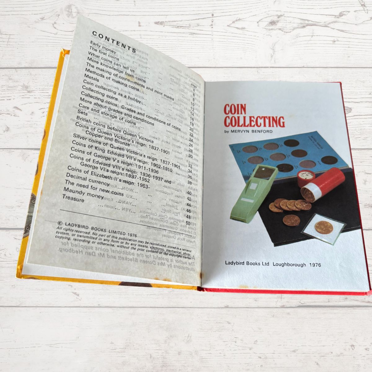 Open book on a wooden surface with a page titled 'Coin Collecting' by Mervyn Benson.