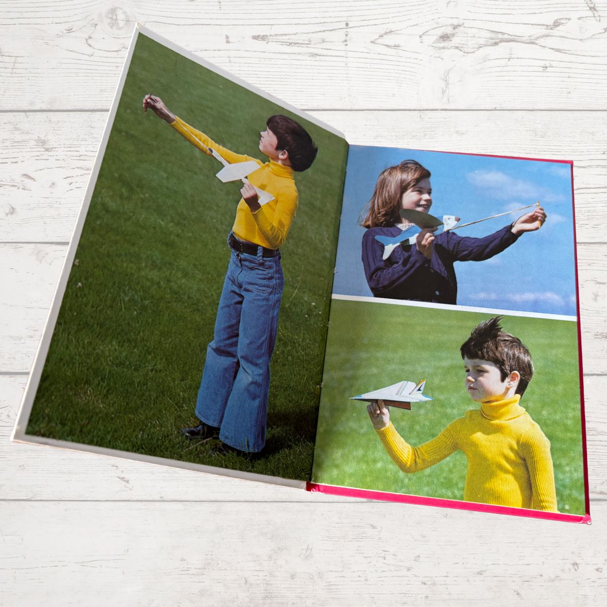 Open book showing three photos of a person with a kite on a grassy field.