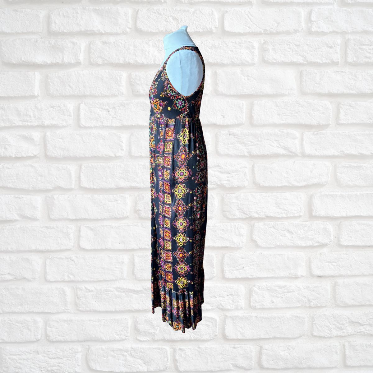 Long dress with a colorful pattern on a white brick wall background