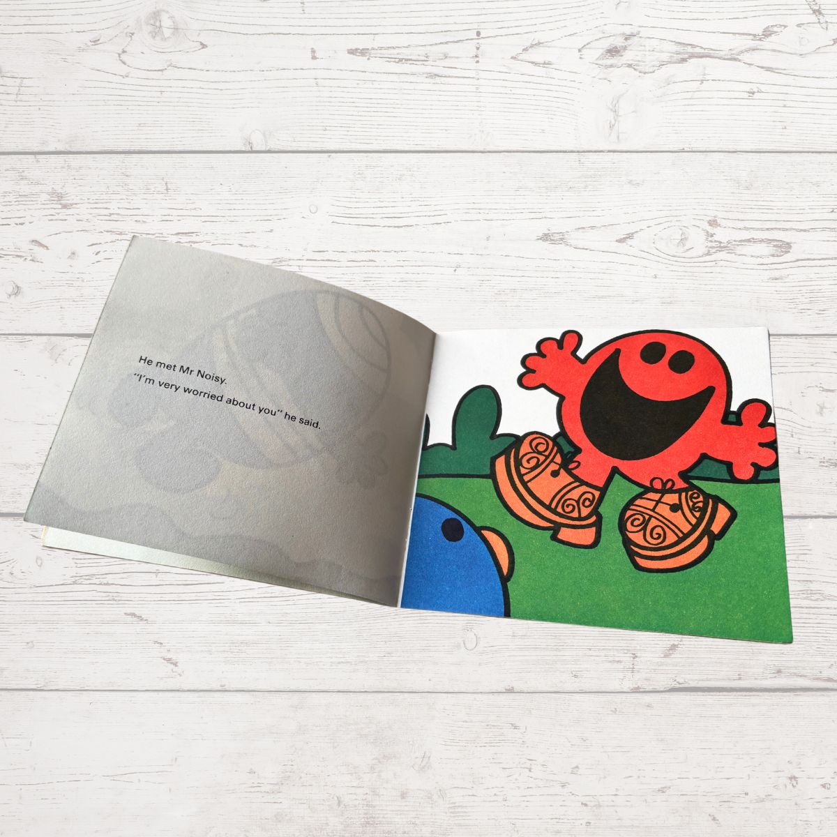 Open book with a colorful illustration of a red character on a white wooden surface