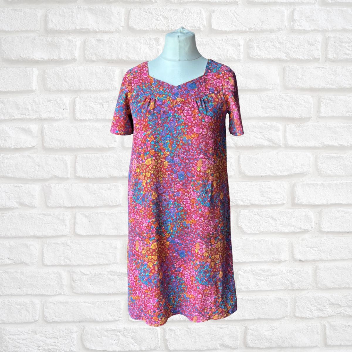 Colorful dress on a mannequin against a white brick wall background
