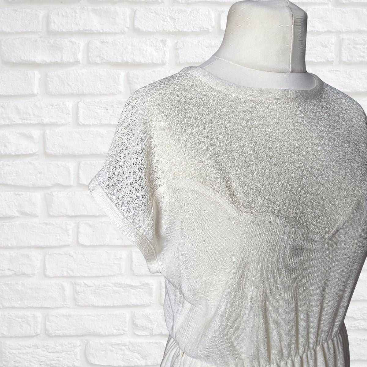 Cream dress on a mannequin against a white brick wall background