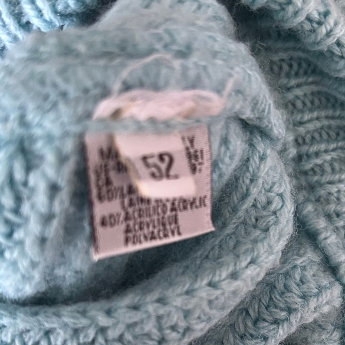 Close-up of a light blue chunky knit yarn ball with a sewn-in size 52 label.