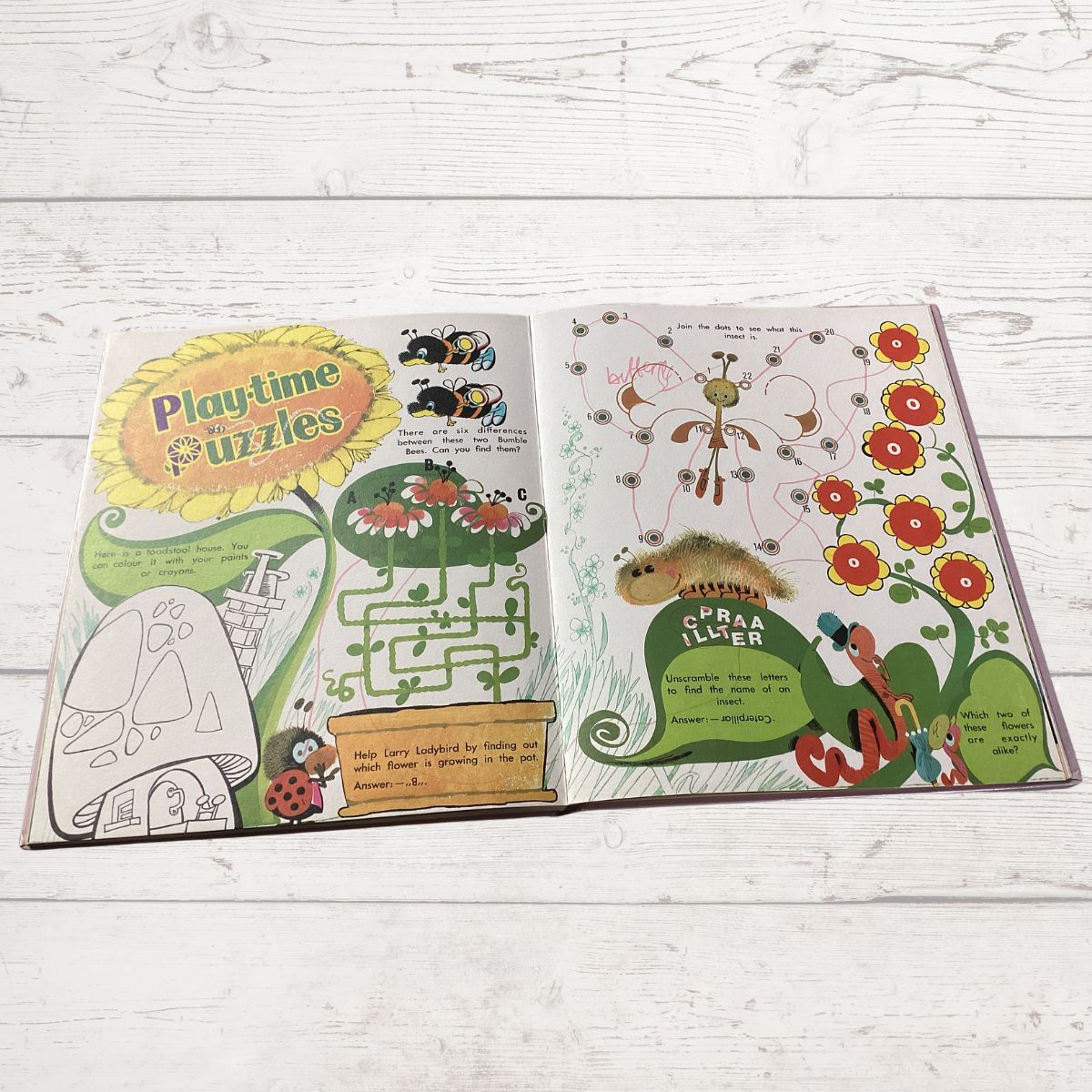 An open children's book spread out on a white wood background, featuring colorful spring-themed illustrations, a flower maze, a flower pollinator puzzle, and a flower identification worksheet.