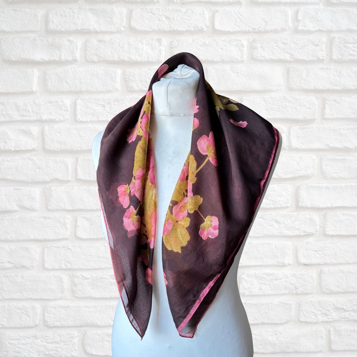 Floral scarf on a mannequin against a white brick wall