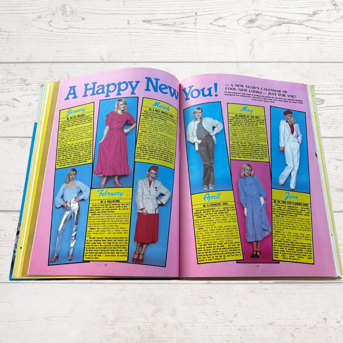 Open book with fashion illustrations and text on a wooden surface