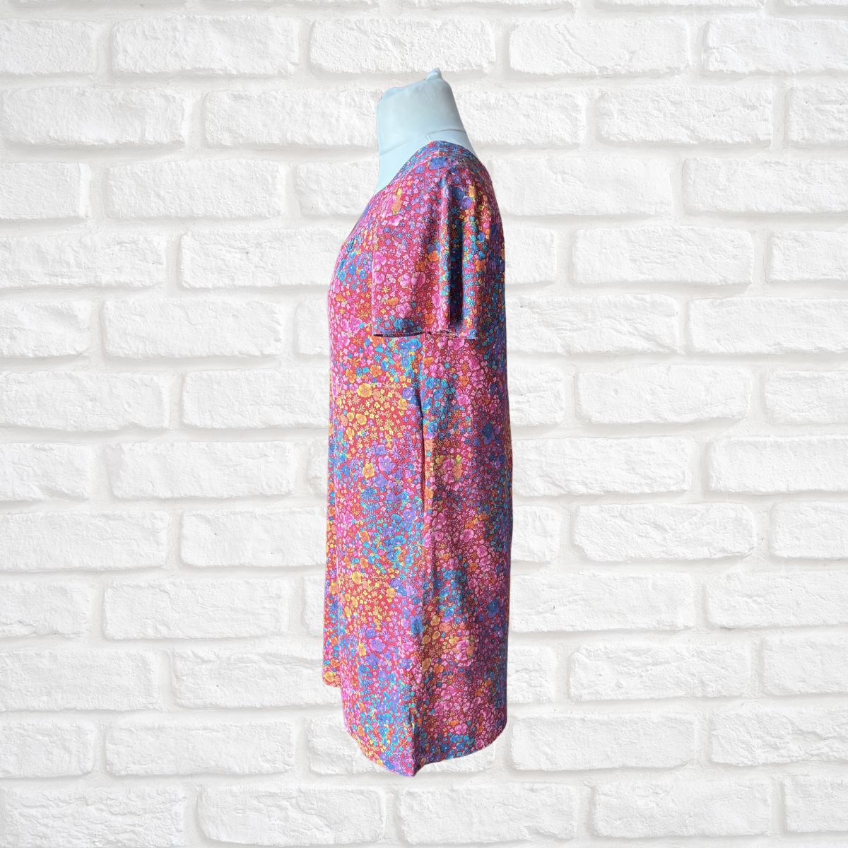Colorful dress with a floral pattern on a white brick wall background