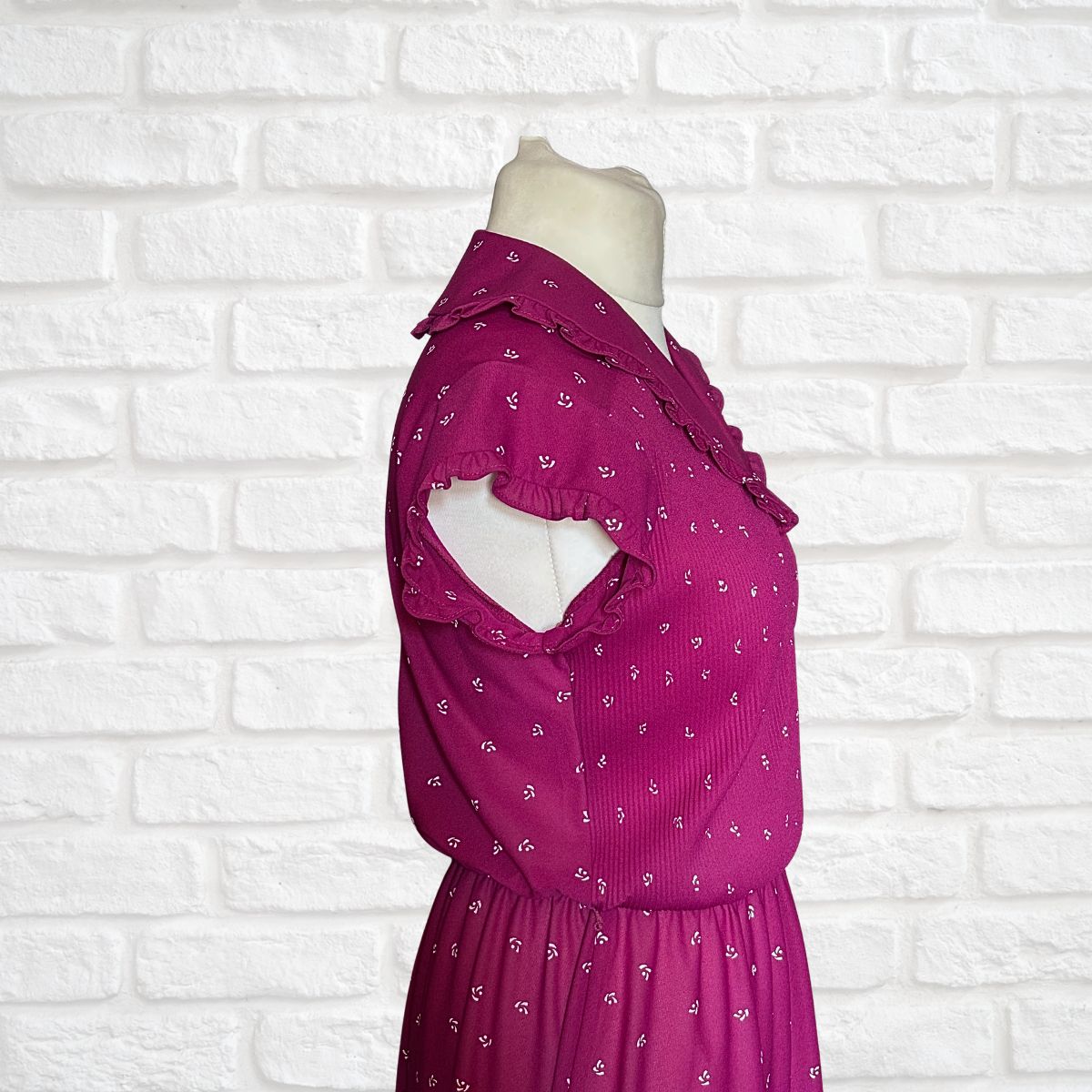 Mannequin wearing a pink dress with a white brick wall background