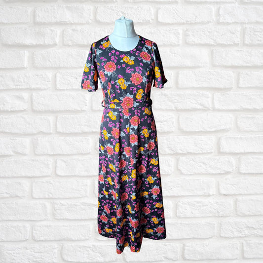 Floral dress on a mannequin against a white brick wall background