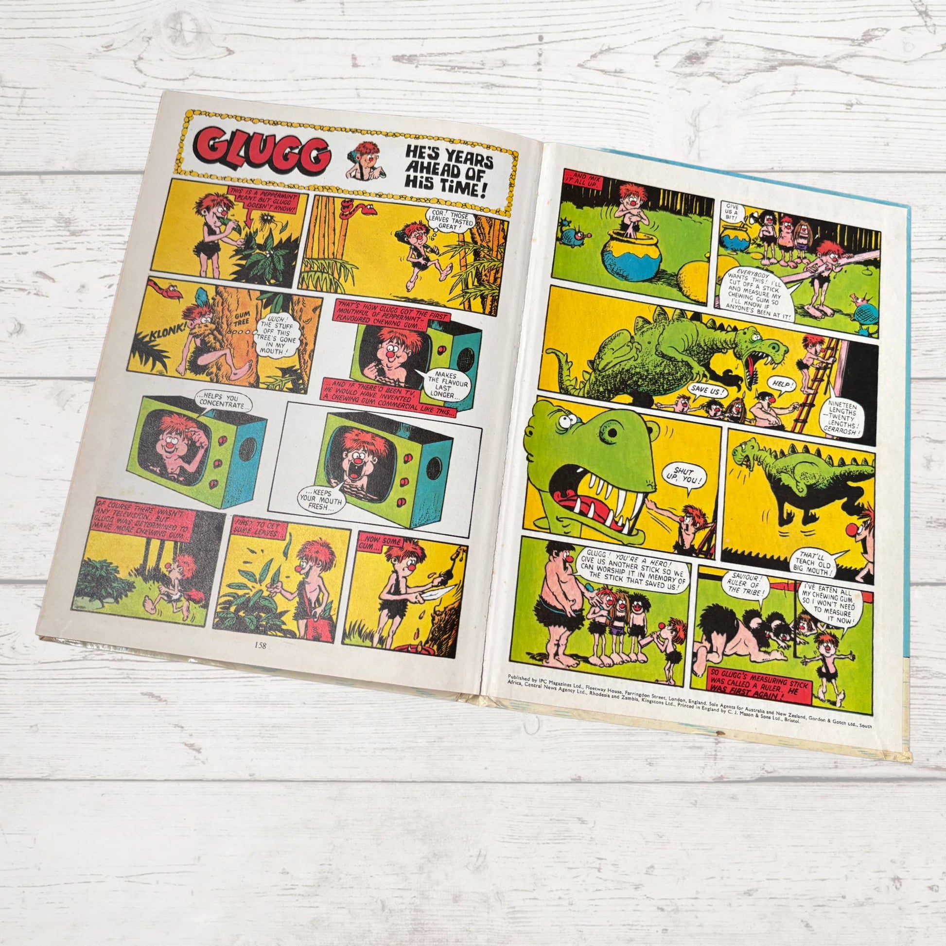 Comic book page with colorful illustrations and text on a wooden surface