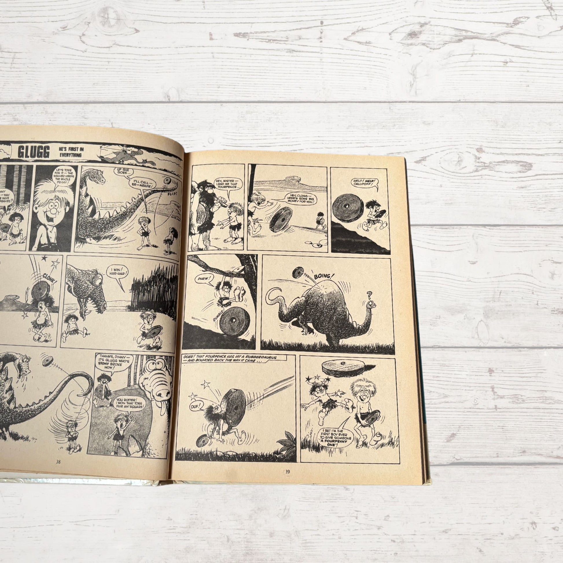 Open comic book with black and white illustrations on a light wooden surface