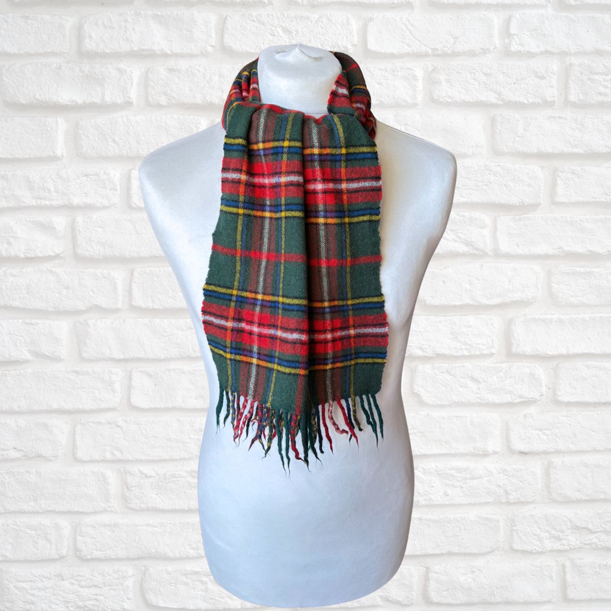 Plaid scarf on a mannequin against a white brick wall background