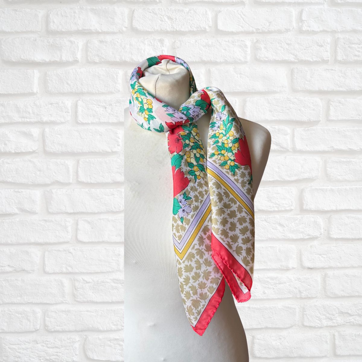 Colorful floral patterned scarf on a mannequin against a white brick wall.