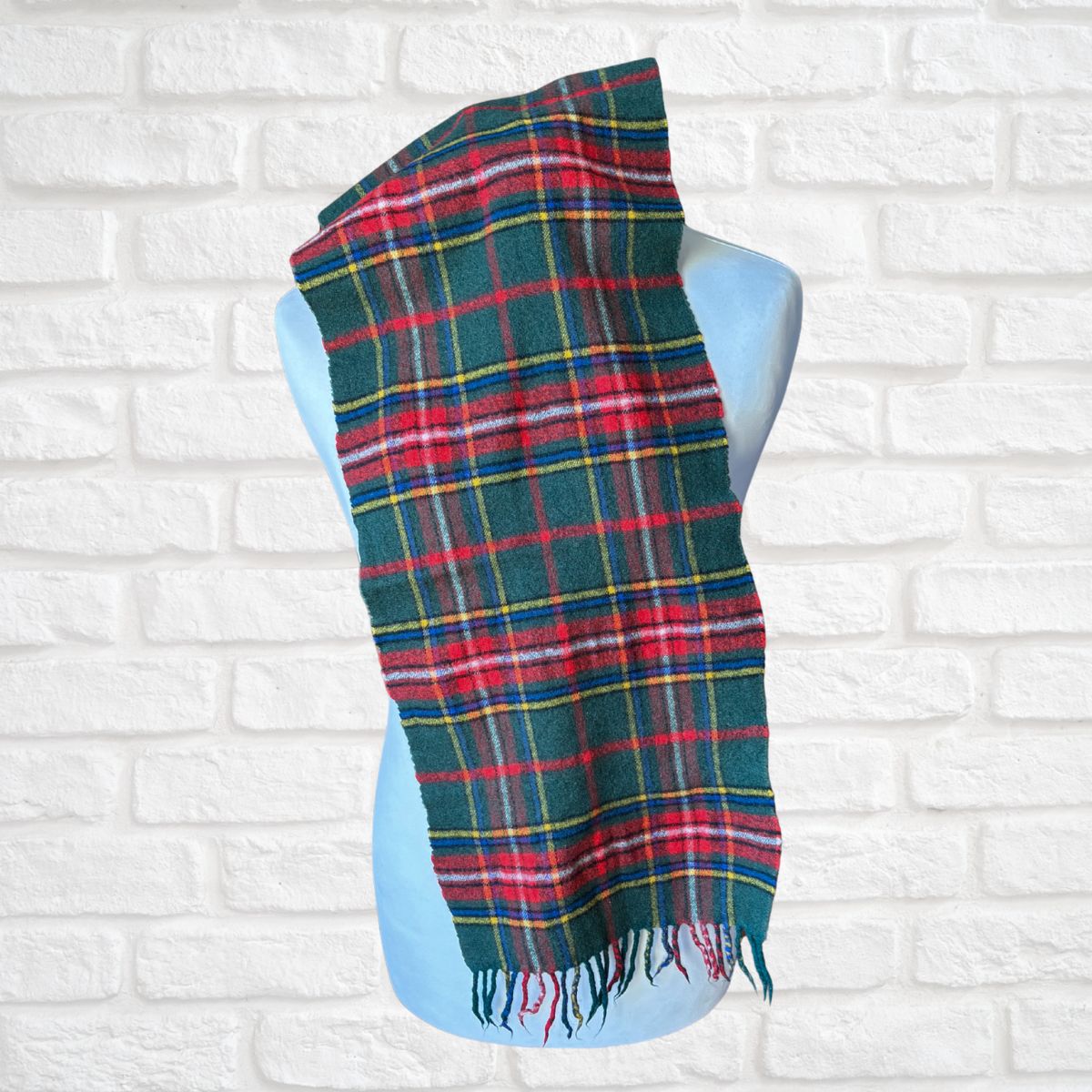 Plaid scarf on a mannequin against a white brick wall background