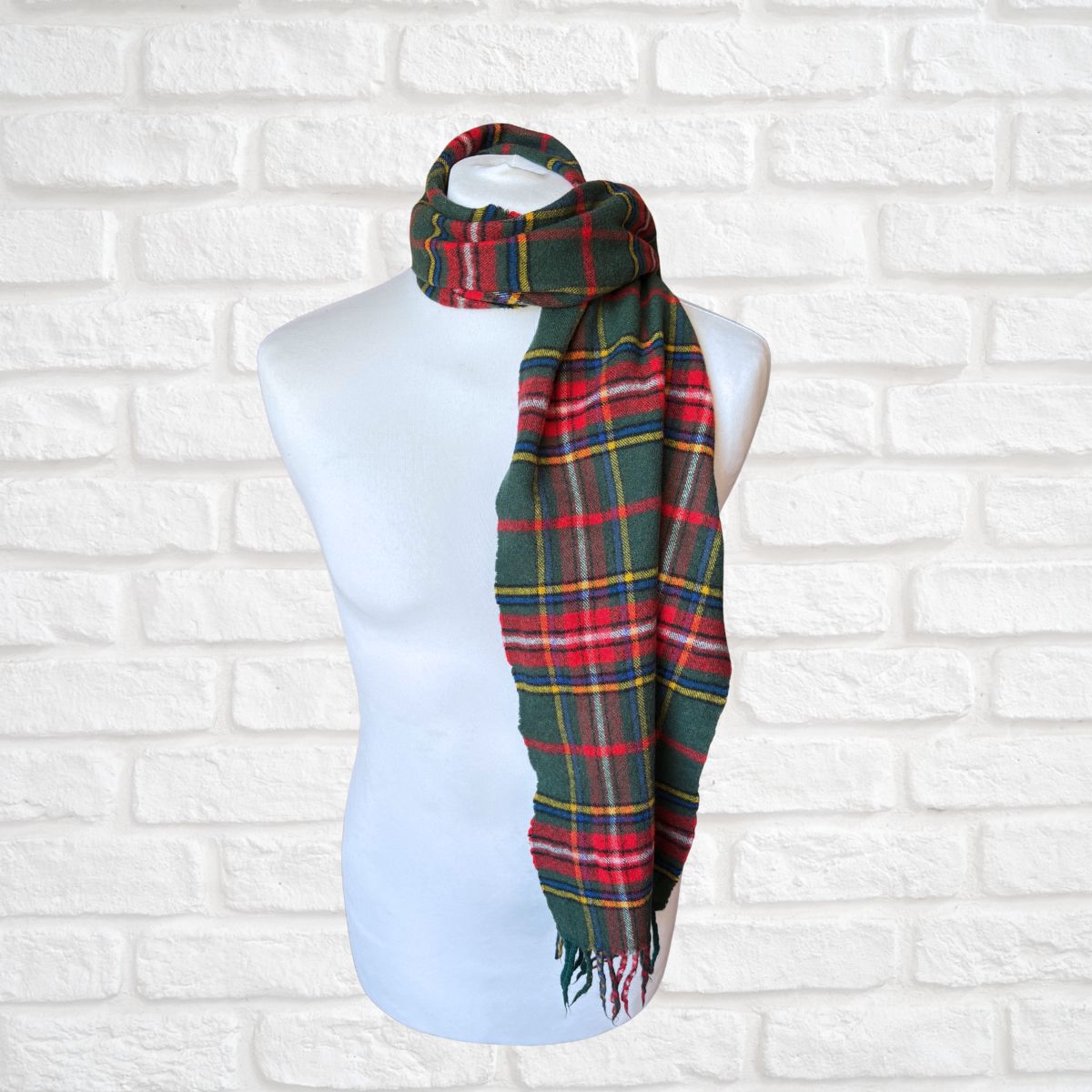 Plaid scarf on a mannequin against a white brick wall background