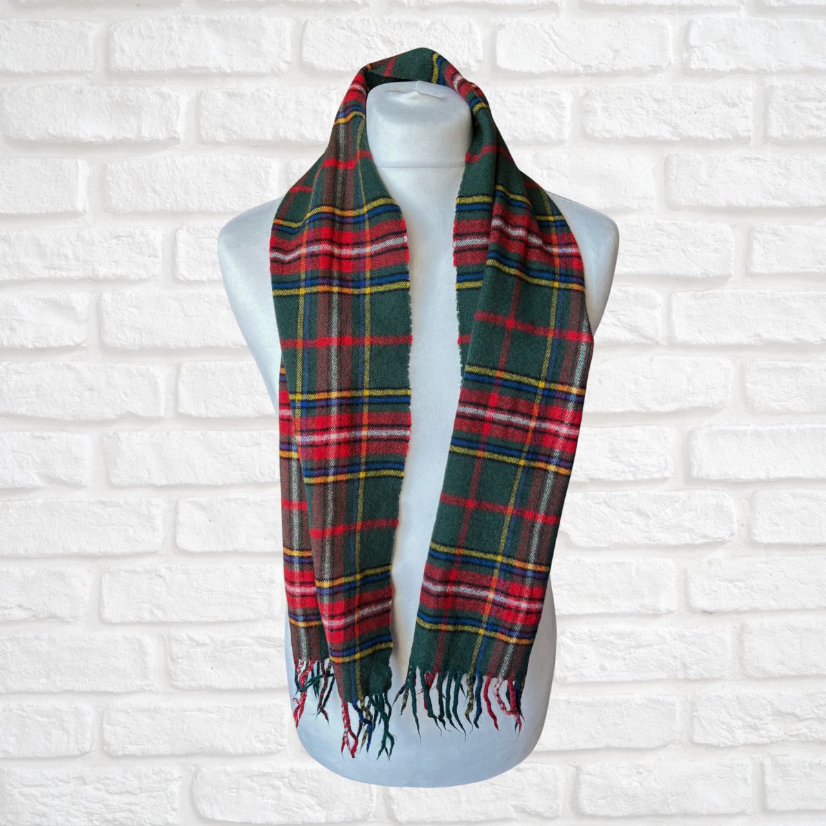 Plaid scarf on a mannequin against a white brick wall background