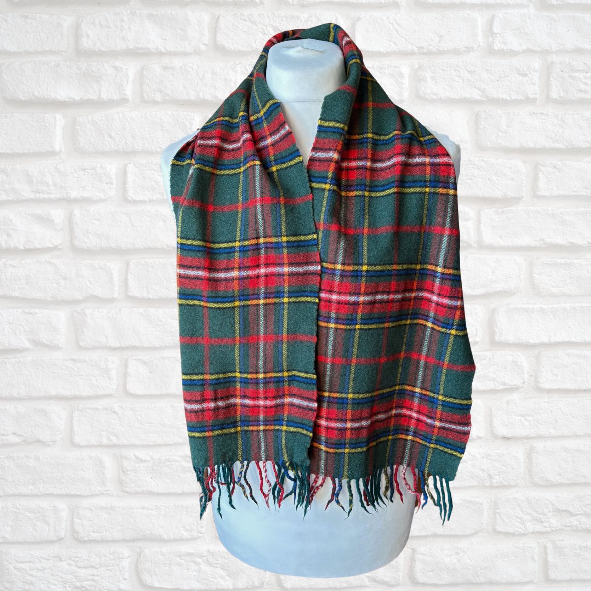 Plaid scarf on a mannequin against a white brick wall background
